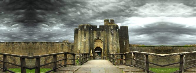 Trip Pauschalreisen Reisetipps - Caerphilly Castle - ein Bollwerk aus dem 13. Jahrhundert in Wales, Vereinigtes Königreich. Mit einem aufsehenerregenden Turm, der schiefer ist wie der Schiefe Turm zu Pisa. Wie jede Burg mit Prestige, hat sie auch einen Geist, „The Green Lady“ spukt in den Gemächern, wo ihr Geliebter den Tod fand. Wo man in Wales oft – und nicht ohne Grund – das Gefühl hat, dass ein Schloss ziemlich gleich ist, ist Caerphilly Castle bei Cardiff eine sehr willkommene Abwechslung. Die Burg ist nicht nur deutlich größer, sondern auch älter als die Burgen, die später von Edward I. als Ring um Snowdonia gebaut wurden.