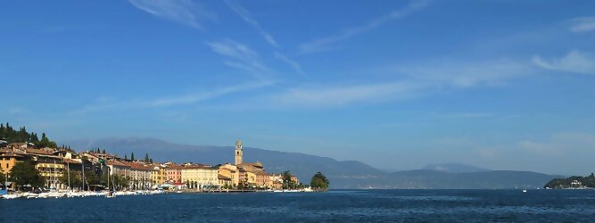 Pauschalreisen beliebte Urlaubsziele am Gardasee -  Mit einer Fläche von 370 km² ist der Gardasee der größte See Italiens. Es liegt am Fuße der Alpen und erstreckt sich über drei Staaten: Lombardei, Venetien und Trentino. Die maximale Tiefe des Sees beträgt 346 m, er hat eine längliche Form und sein nördliches Ende ist sehr schmal. Dort ist der See von den Bergen der Gruppo di Baldo umgeben. Du trittst aus deinem gemütlichen Hotelzimmer und es begrüßt dich die warme italienische Sonne. Du blickst auf den atemberaubenden Gardasee, der in zahlreichen Blautönen schimmert - von tiefem Dunkelblau bis zu funkelndem Türkis. Majestätische Berge umgeben dich, während die Brise sanft deine Haut streichelt und der Duft von blühenden Zitronenbäumen deine Nase kitzelt. Du schlenderst die malerischen, engen Gassen entlang, vorbei an farbenfrohen, blumengeschmückten Häusern. Vereinzelt unterbricht das fröhliche Lachen der Einheimischen die friedvolle Stille. Du fühlst dich wie in einem Traum, der nicht enden will. Jeder Schritt führt dich zu neuen Entdeckungen und Abenteuern. Du probierst die köstliche italienische Küche mit ihren frischen Zutaten und verführerischen Aromen. Die Sonne geht langsam unter und taucht den Himmel in ein leuchtendes Orange-rot - ein spektakulärer Anblick.